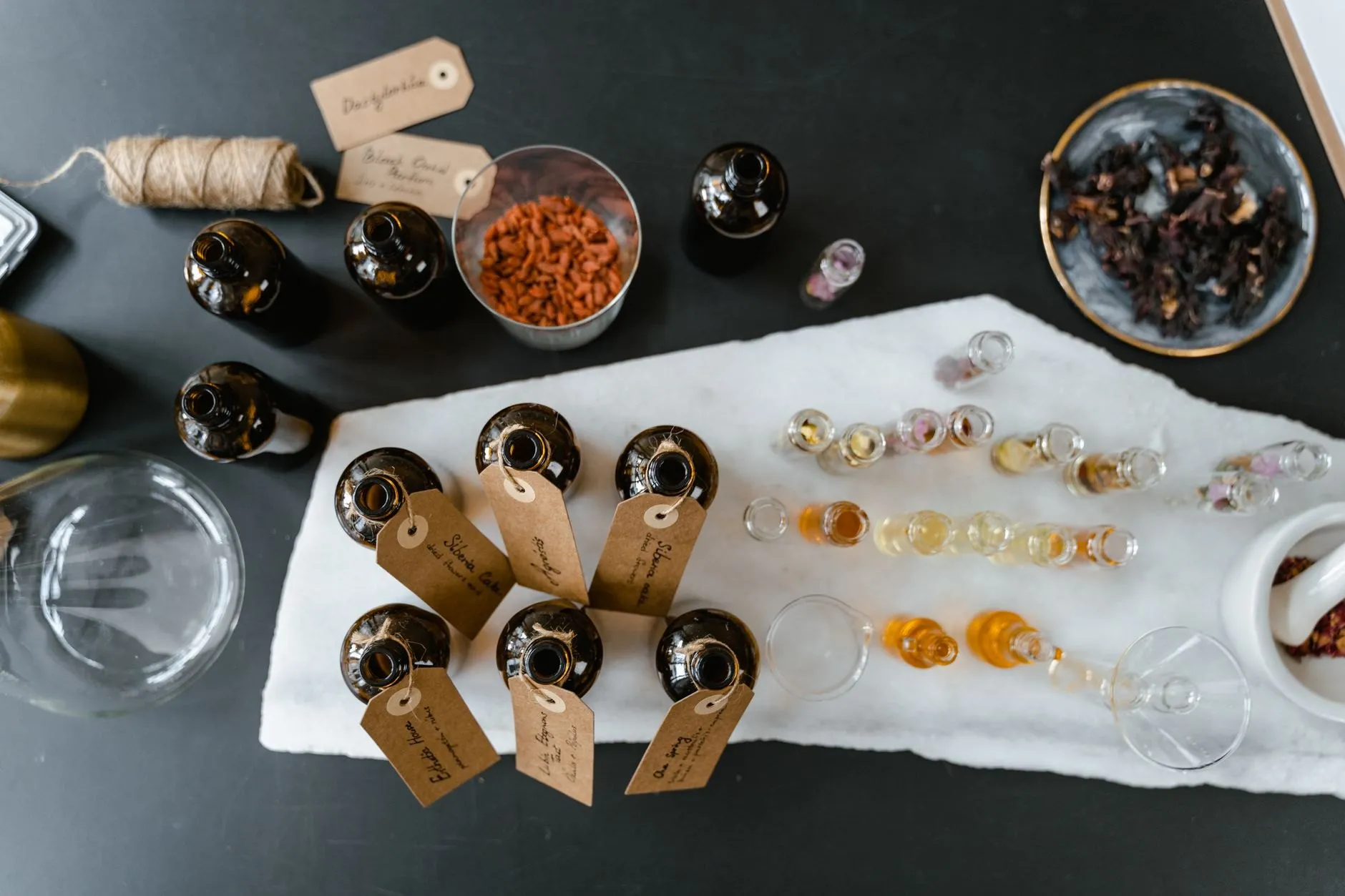 Amber bottles with handwritten tags laid on a marble slab, seen from above