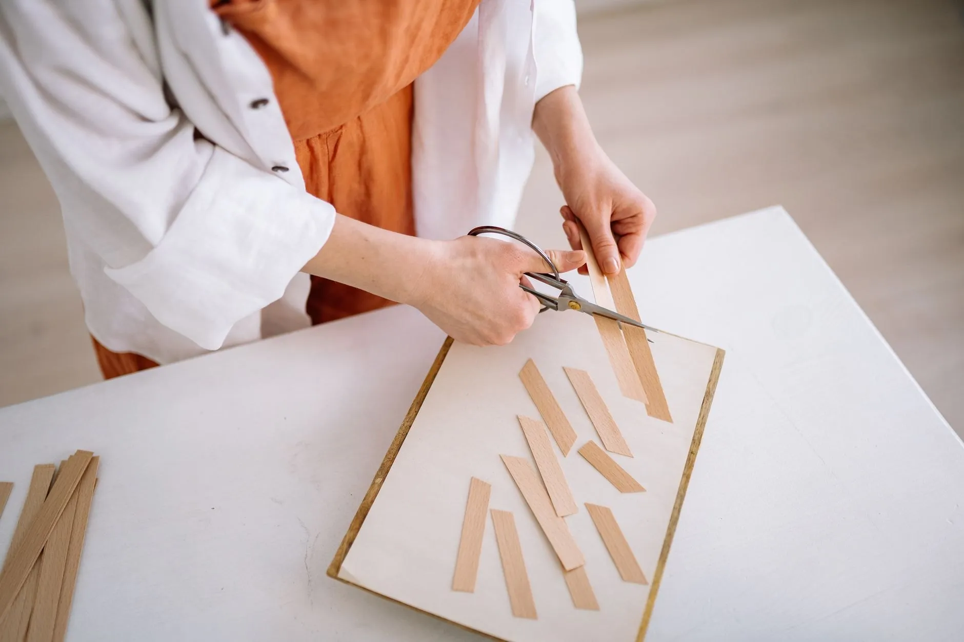 The perfumer's assistant cutting paper blotter strips at a white table