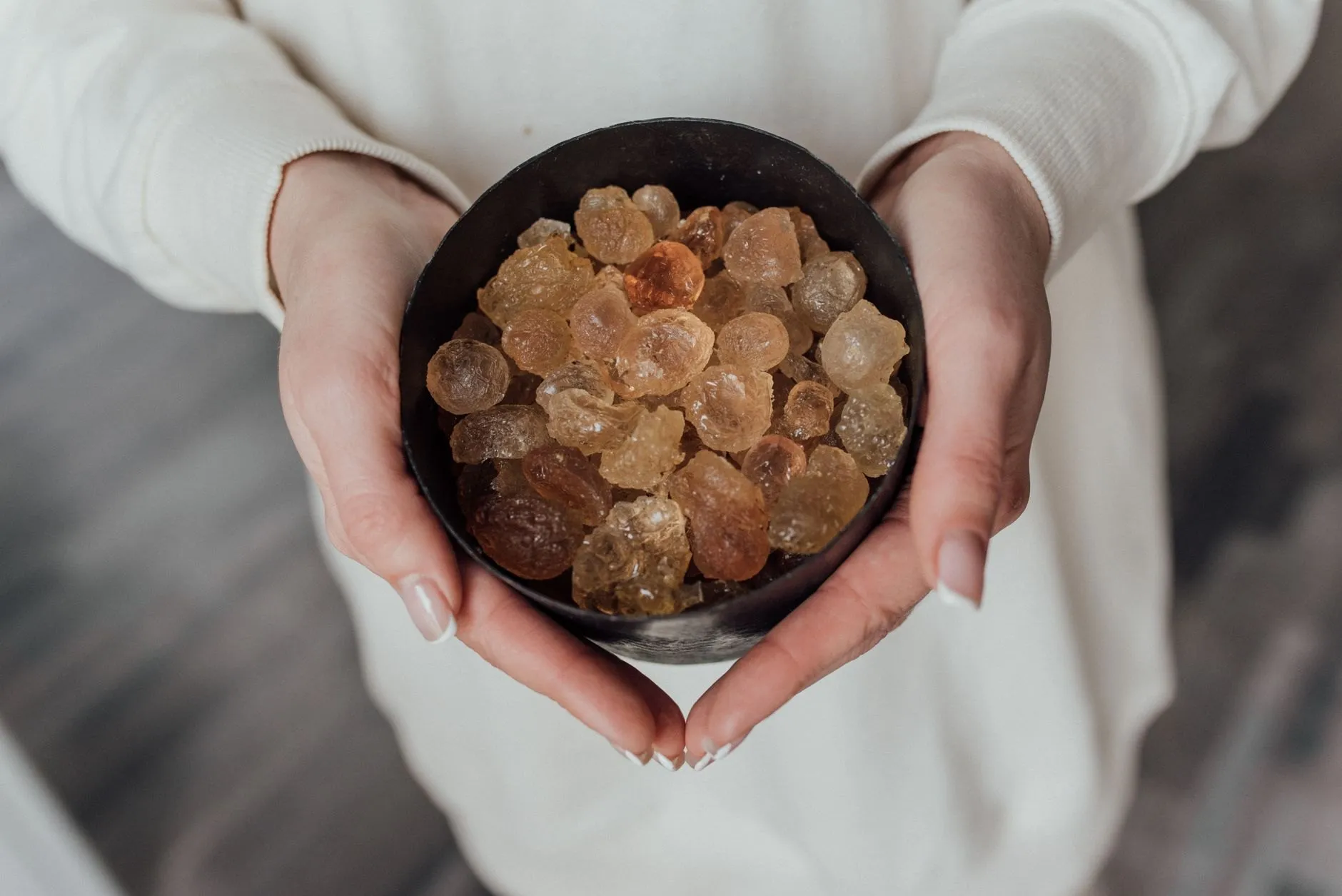 Two hands holding a bowl of golden resin tears