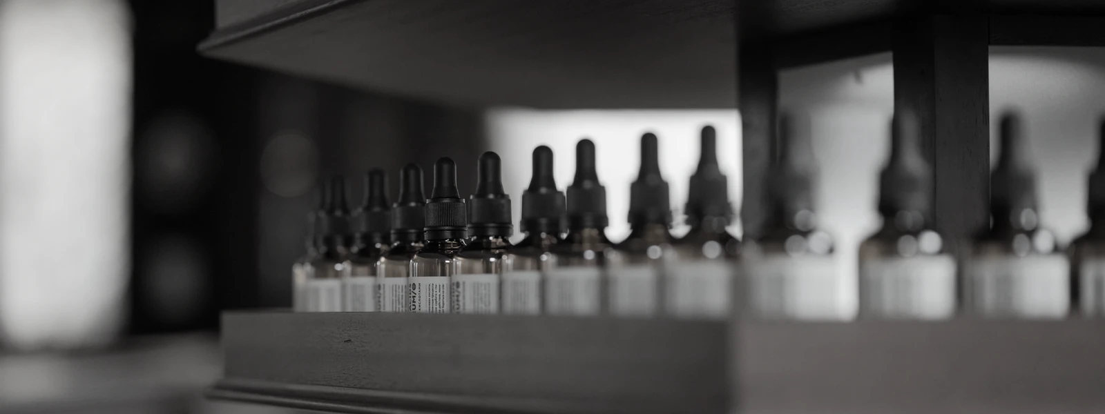 Rows of dropper bottles on a workshop shelf, printed at the dilution the house evaluates at.